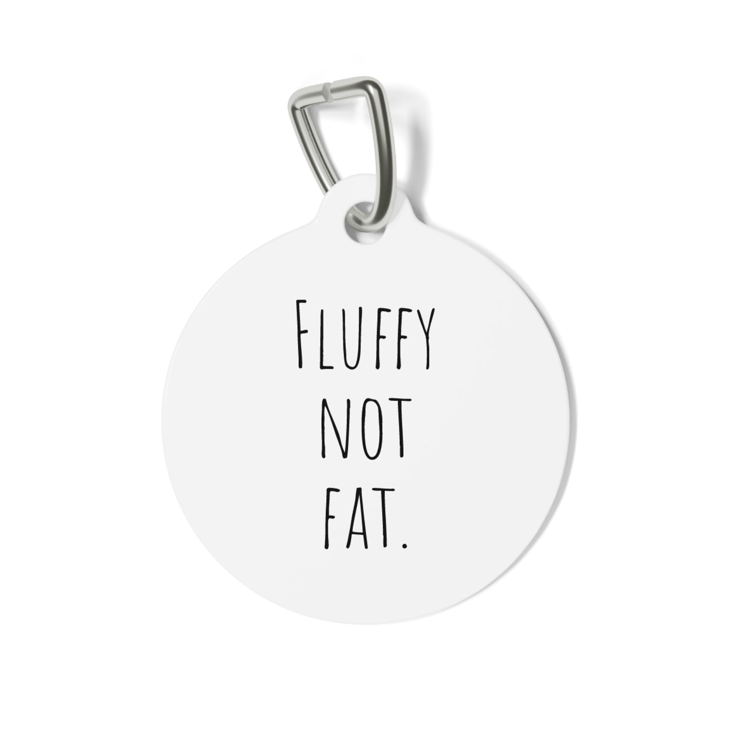 A round white dog tag with the text 'FLUFFY NOT FAT' in black capital letters, attached to a metal clip.