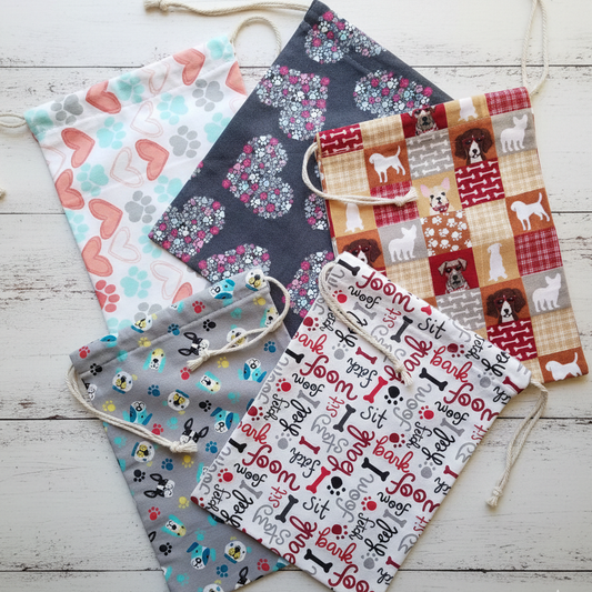 Collection of fabric gift bags with various patterns on a wooden surface