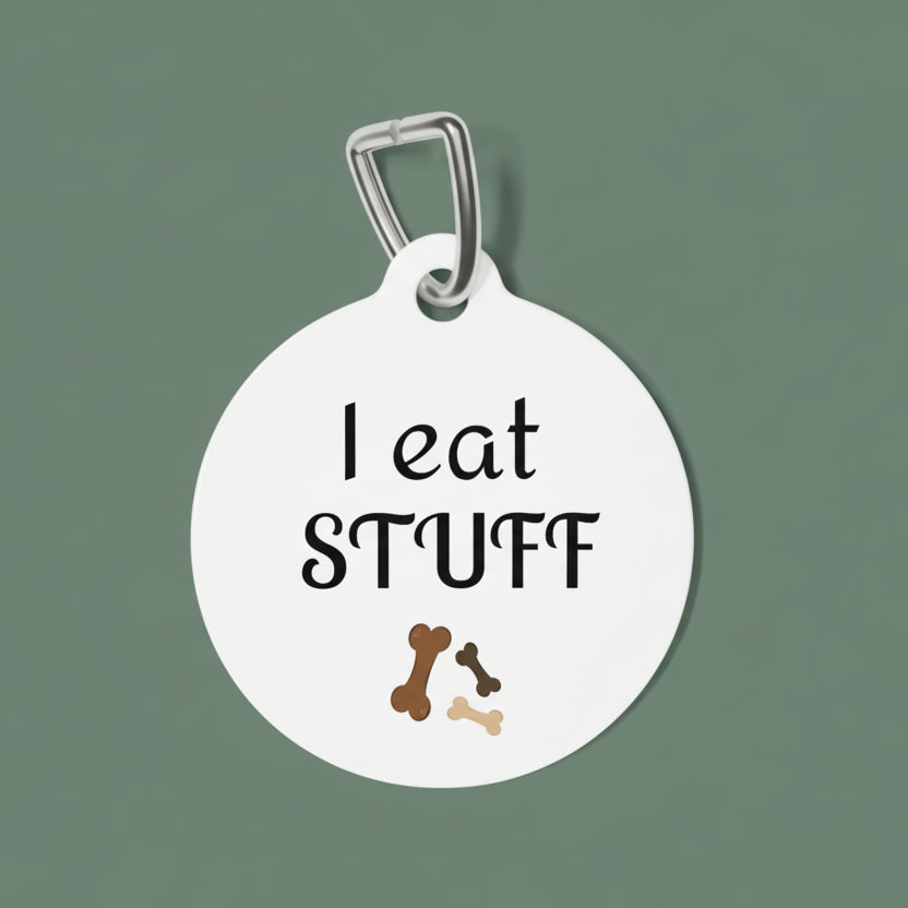 Round white pet tag with 'I eat STUFF' text and dog bone illustrations on a white background