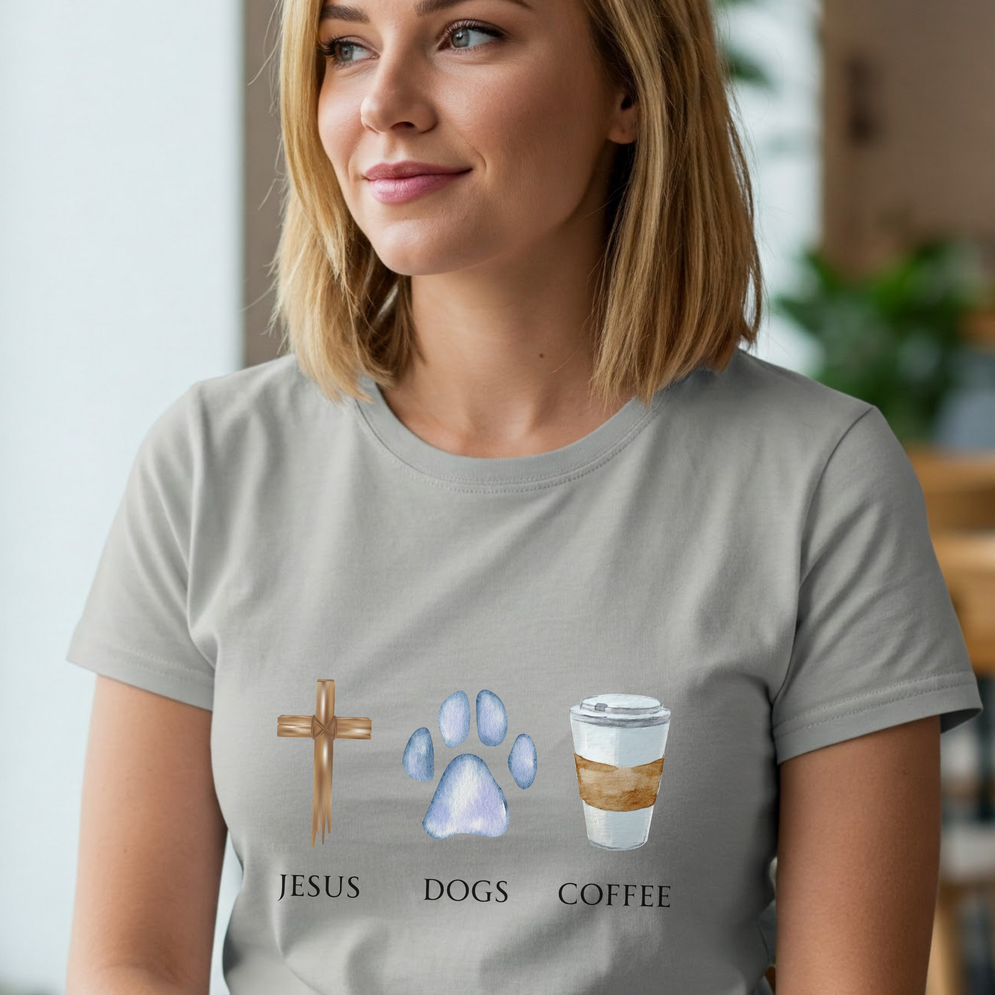 Woman wearing a gray t-shirt with 'Jesus', 'Dogs', and 'Coffee' graphics.