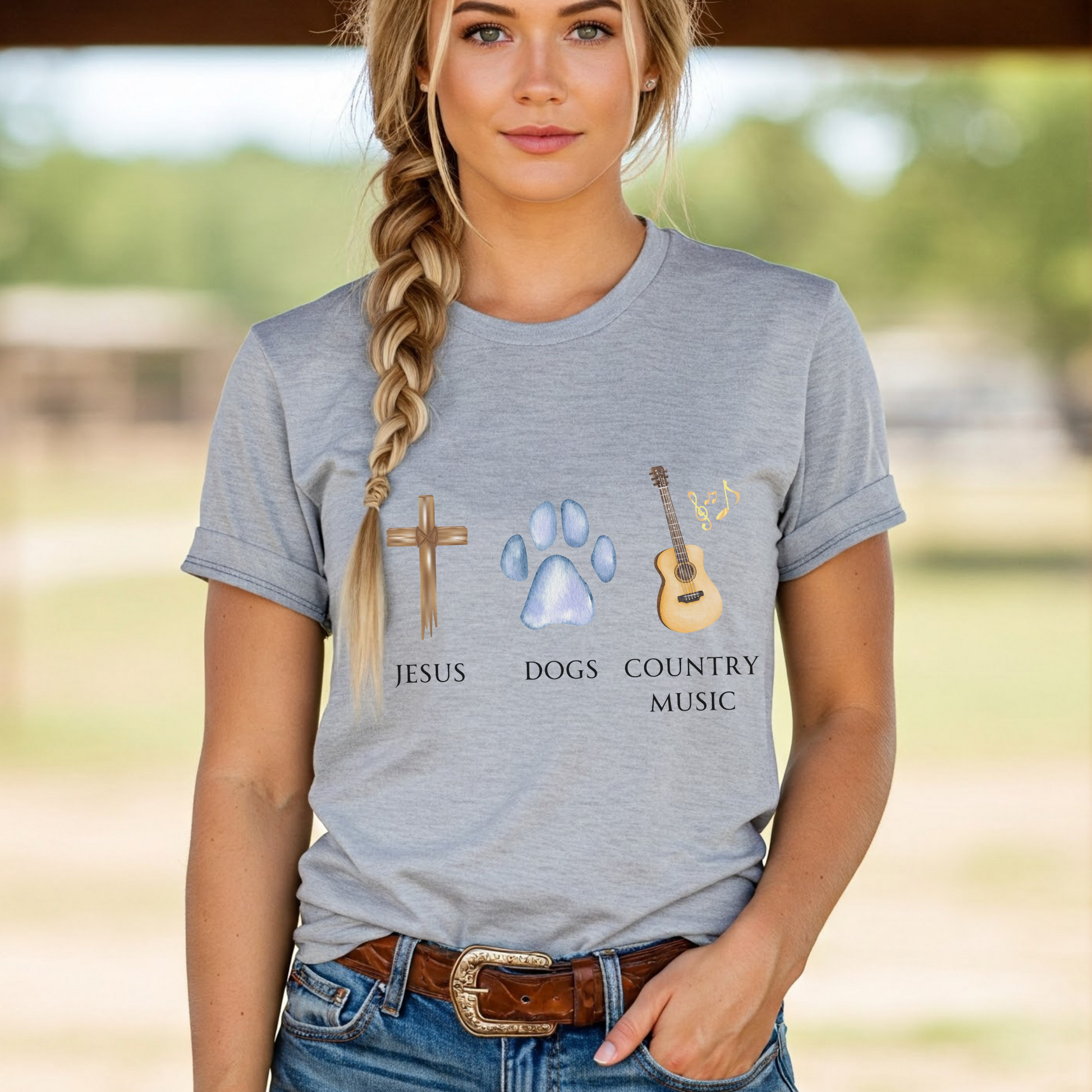 Woman wearing a gray t-shirt with 'Jesus', 'Dogs', and 'Country Music' graphics and text.