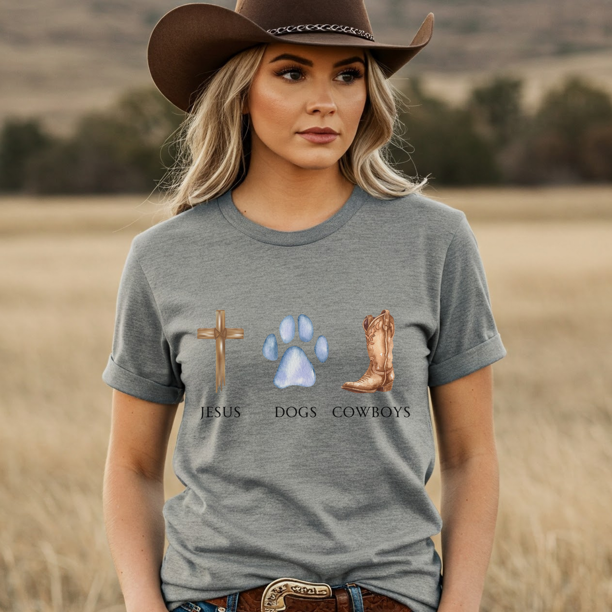 Woman wearing a gray t-shirt with religious and cowboy-themed graphics in a field.