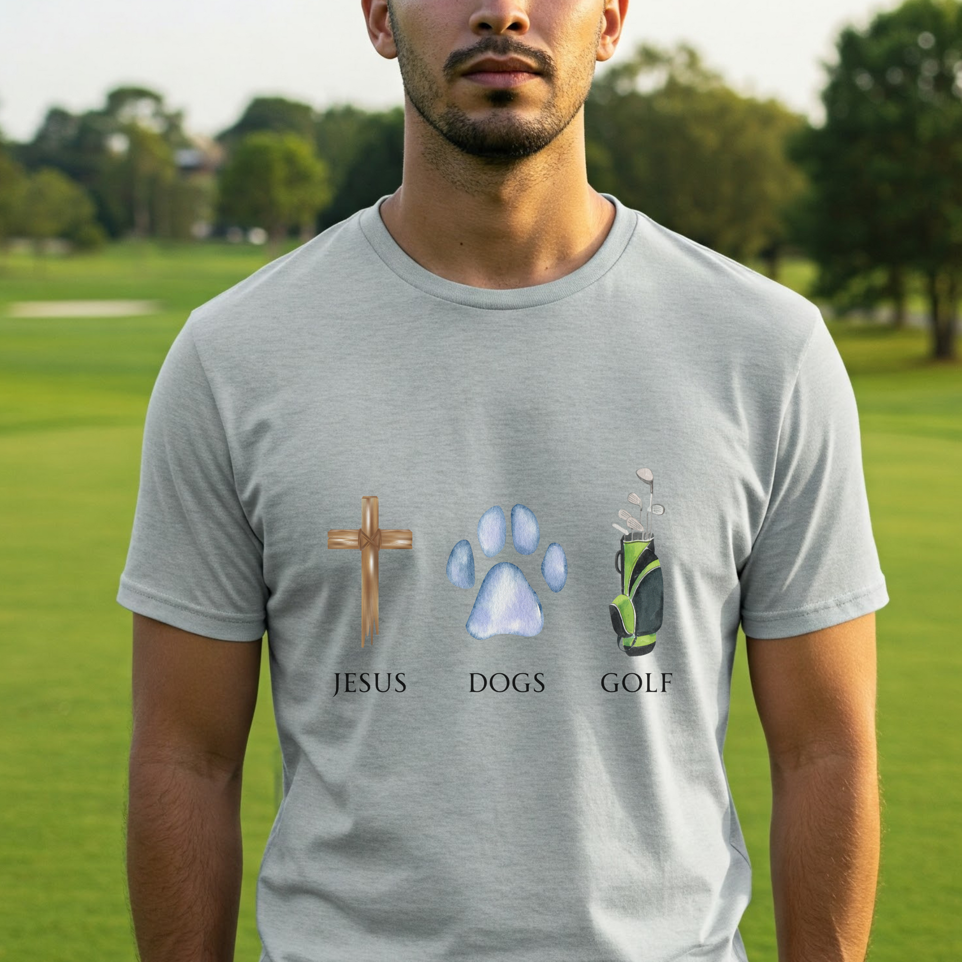 Man wearing a gray t-shirt with 'Jesus', 'Dogs', and 'Golf' symbols on a golf course background