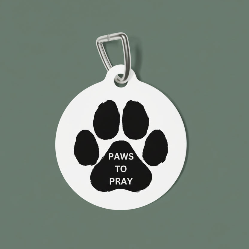 Pet tag with black paw print and 'PAWS TO PRAY' text on a white background