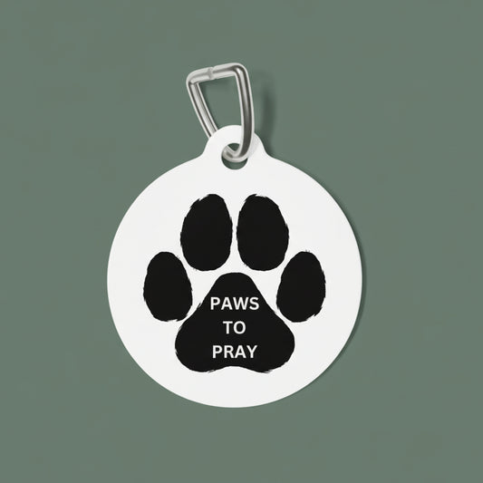 Pet tag with black paw print and 'PAWS TO PRAY' text on a white background