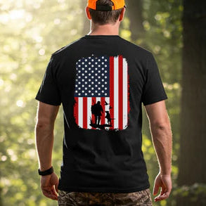 Man wearing a black t-shirt with an American flag design and a duck hunter in a forest