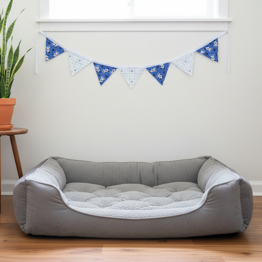 Gray pet bed in a room with a plant and decorative banner