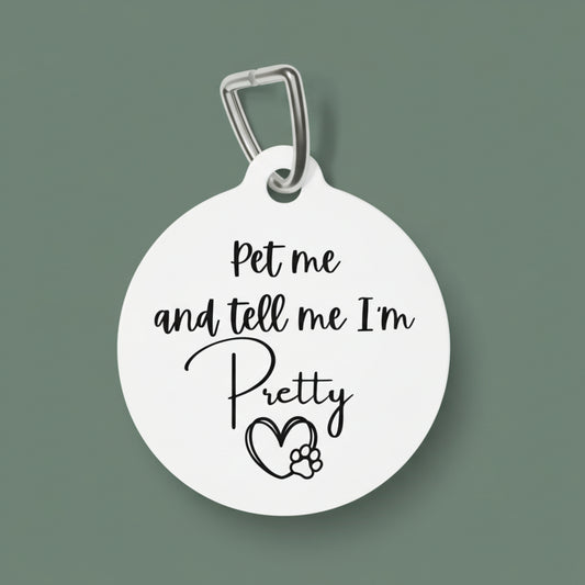 Round white pet tag with black text 'Pet me and tell me I'm Pretty' and a heart with paw print on a white background.