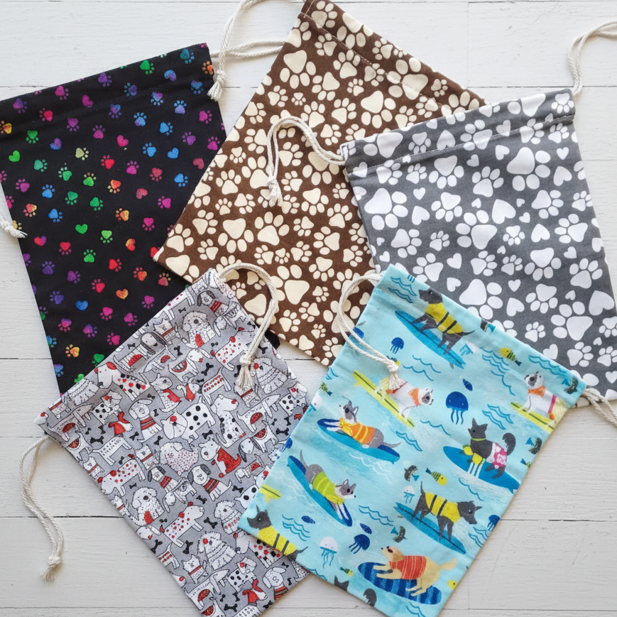Five drawstring bags with various patterns on a white wooden surface