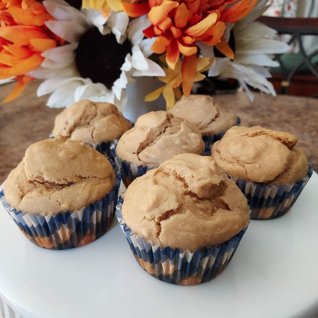 Muffins on a white surface with a decorative flower arrangement in the background