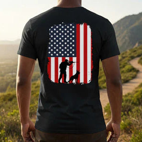 Person wearing a black t-shirt with an American flag and military soldier design outdoors.