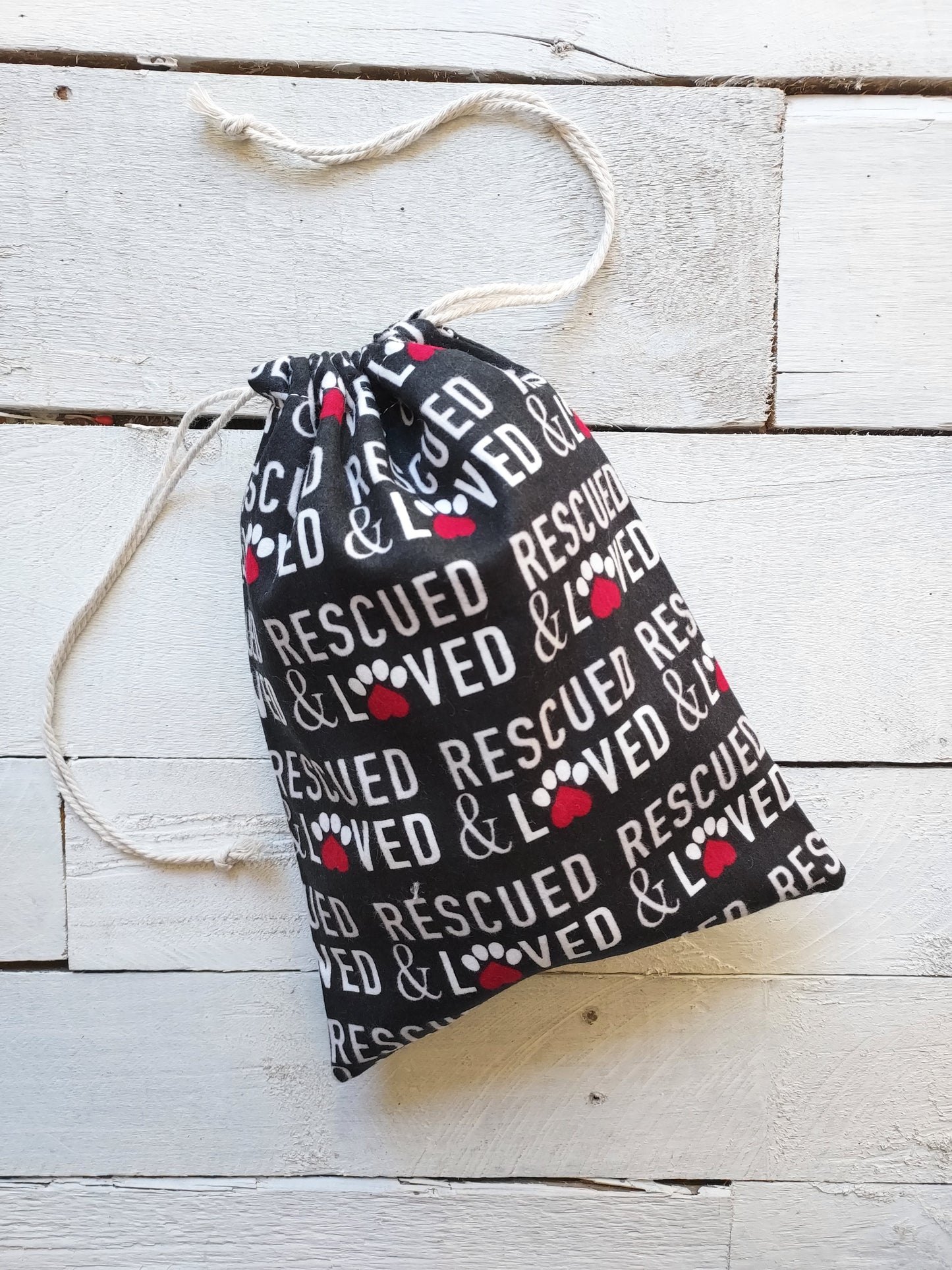 Black bag with 'Rescued & Loved' text on a wooden surface