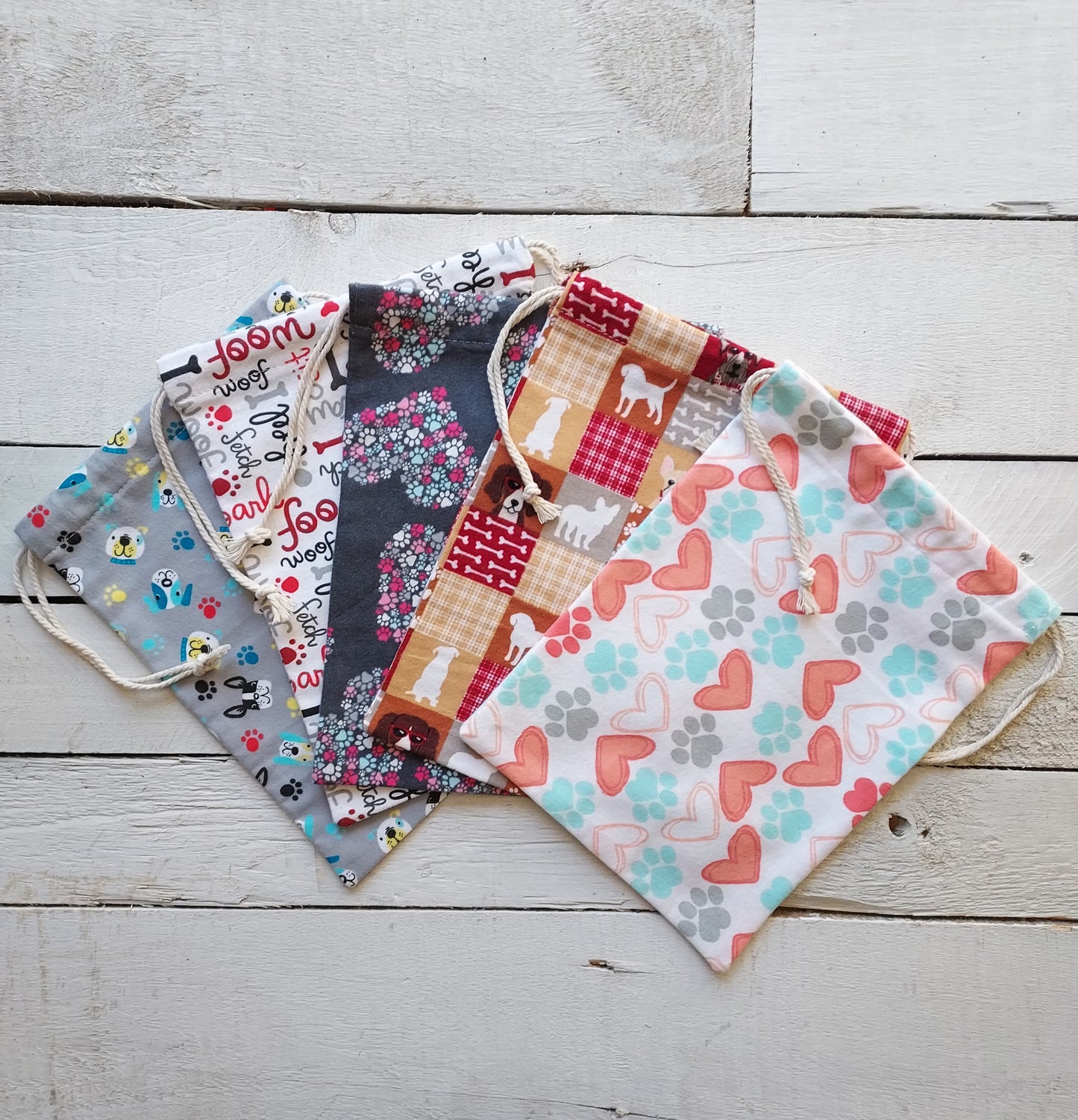 Colorful reusable fabric bags with various dog patterns on a wooden surface
