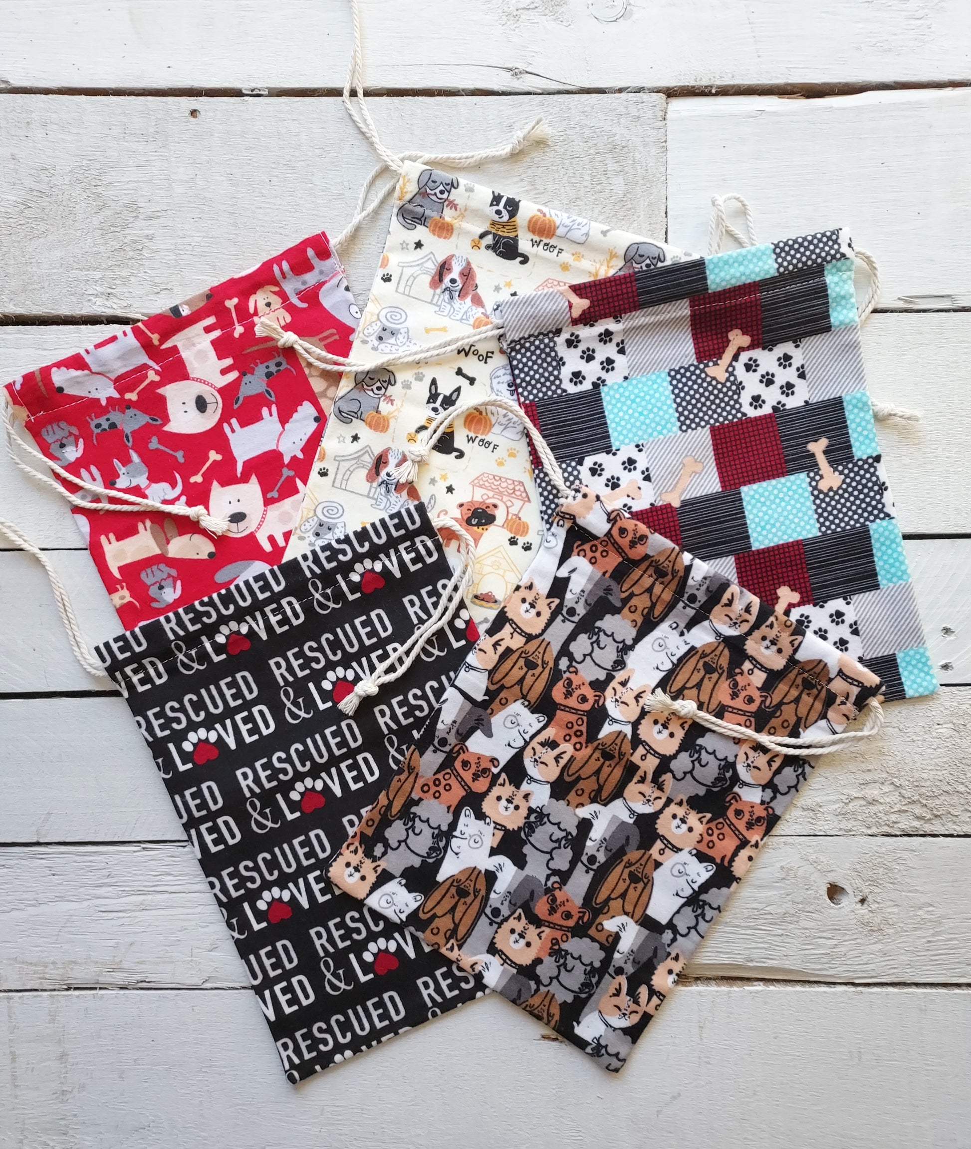 Collection of fabric bags with dog-themed patterns on a wooden surface