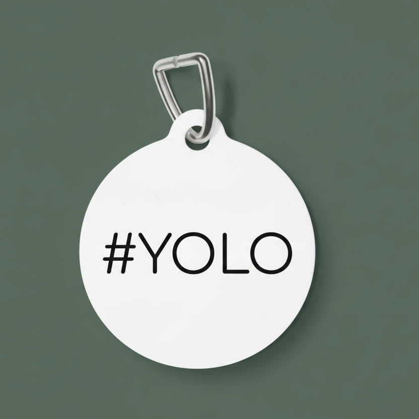 Round white dog tag with '#YOLO' text on a white background